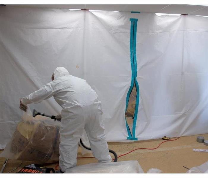 Person using protective gear while performing mold containment, mold barriers